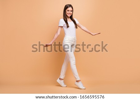 Full length photo of candid attractive lovely girl go walk enjoy her spring time holiday feel cool wear modern youth style clothing isolated over beige color background