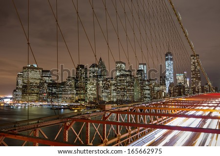 View of Brooklyn Bridge with traffic and Manhattan skyline by night