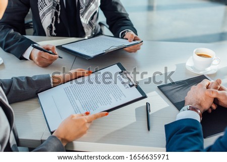 cropped view of business partners holding contract on meeting in office