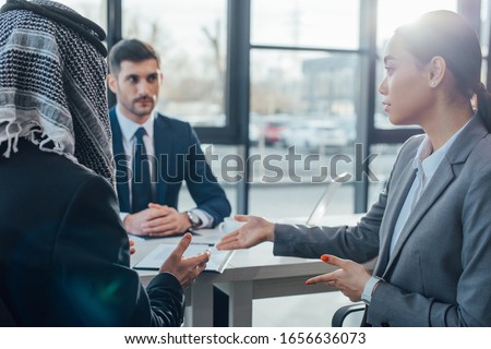 multicultural business partners talking on meeting with translator in office