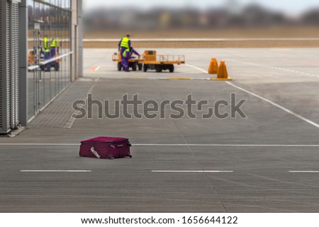 The suitcase lost by the airport staff lies on the floor. Concept of lost luggage. Royalty-Free Stock Photo #1656644122