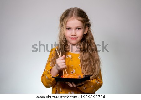 Japanese cuisine home delivery. The girl drops the roll, learning to hold sticks. Delicious. White background. Long hair, yellow dress