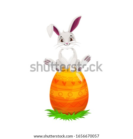 Easter bunny sitting on painted egg, Easter religious holiday and egghunting party. Vector white rabbit or hare animal with cute ears on spring green grass with orange egg and yellow pattern