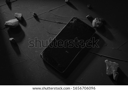 Broken screen phone on concrete background with the hard light, shadows