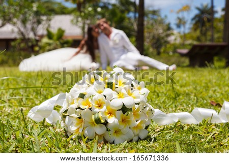 wedding bouquet of frangipani and newlyweds on the grass