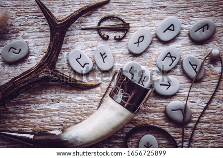 Flat lay view of rune stones with various viking era style objects. Ancient divination and vikings lifestyle concept. Royalty-Free Stock Photo #1656725899