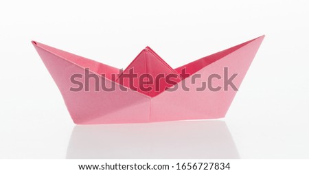 Pink origami boat on white background.
