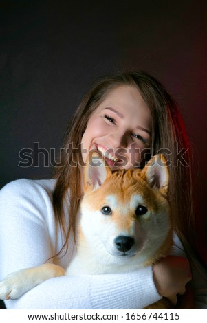 Girl with shiba inu. Beautiful girl holds a shiba inu dog in her arms. Studio photography, dark background.