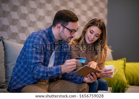 Young couple with tablet at home.They are websurfing on the net with tablet.People and technology concept.