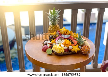 Juicy ripe tropical Thai fruits sliced and beautifully laid on a wooden dish.