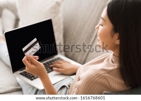 Order online. Girl making purchases on laptop computer, holding credit card