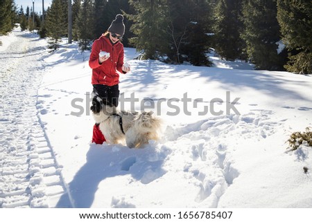 happy woman and dog playing in fresh snow