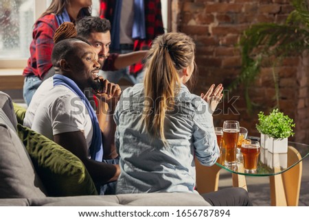 Excited group of people watching football, sport match at home. Multiethnic group of friend, fans cheering for favourite national basketball, tennis, soccer, hockey team. Concept of emotions, support.