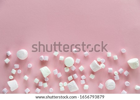 Background or texture of pink and white mini marshmallows on pink background with free space for text, sweet food