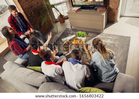 Excited group of people watching rugby, sport match at home. Multiethnic group of emotional friend, fans cheering for favourite national team, drinking beer. Concept of emotions, support, enjoyment.