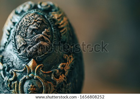 Close up photo vinage Easter egg decorated with papier-mache hand made, beautiful decorations on egg at stand, pictures on egg, look like stones eggs, jewellery, on wooden background.