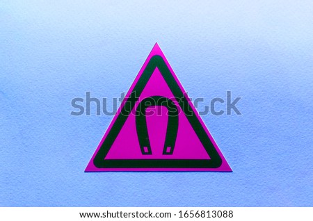 warning sign magnetic field in a purple triangle on a blue background close up