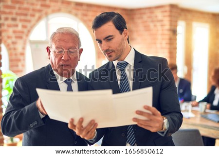 Two business workers working together. Speaking and reading documents standing at the office