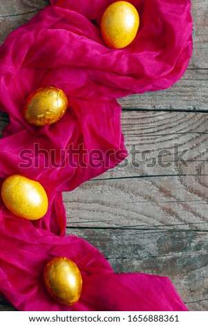 Colorful Easter eggs and silk textile material on the wooden background. Festive Easter holiday concept. View from above. Copy space. Top view
