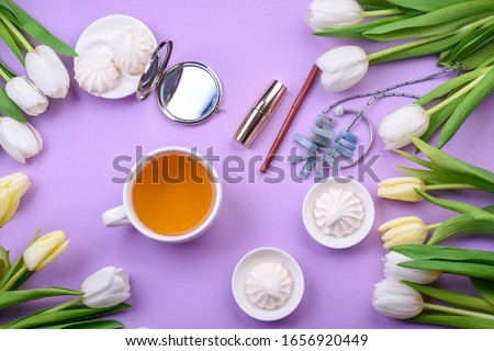  white tulips and white mug with tea, sweets on pink background. Flat lay. womanlike desk with cosmetics, lipstick and white flowers on pink background. 