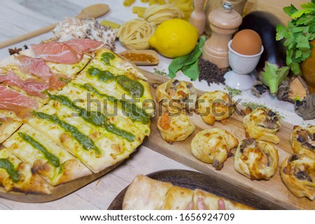 Home made pizza with different form and preparation cooking. Served on wooden plates and woodenboards, with vegetables and spoon in wood decoration.