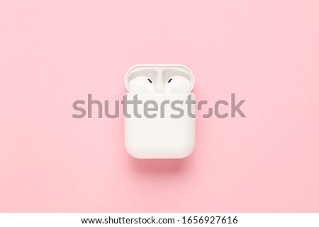 White wireless earphones on pink background