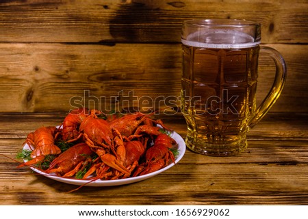 Glass of beer and boiled crayfish on rustic wooden table
