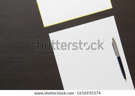 Template of white paper with pen and envelope on dark wenge color wooden background. Concept of business plan and strategy. Stock photo with empty space for text and design.