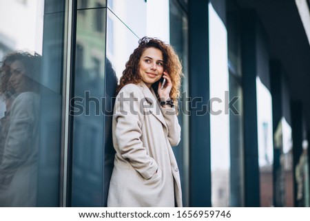 Young woman with curly hair using phone at the street