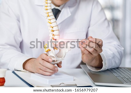 The doctor shows on the spine the place where the intervertebral hernia appears.