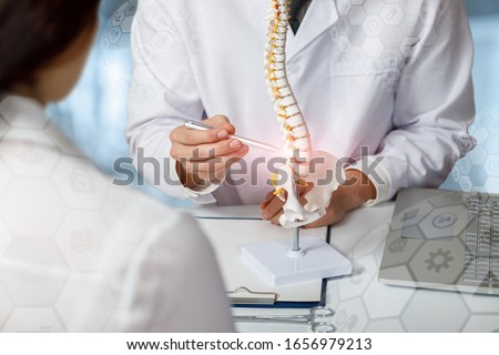 Doctor advising patient about problem areas of the spine on a blurred background.