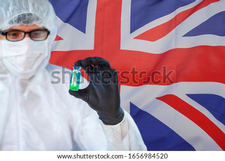 Concept of coronavirus quarantine, new virus - covid-19, test tube with coronovirus in the hands of a virologist in a chemical laboratory against on the background of the flag of Great Britain