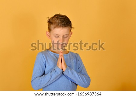 A boy prays kneeling, religious and devout children.