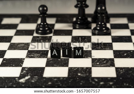 Acronym AIM for Access and Identity Management concept represented by black and white letter tiles on a marble chessboard with chess pieces