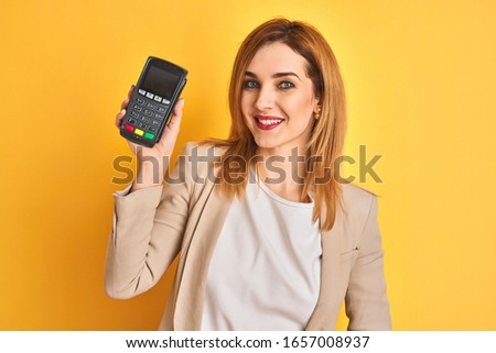 Redhead caucasian business woman holding point of sale terminal over isolated background with a happy face standing and smiling with a confident smile showing teeth