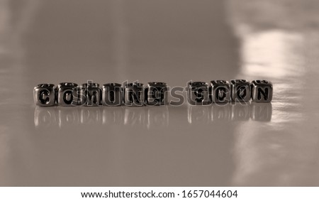 Coming soon -  word from metal blocks - concept sepia tone photo on shine background
