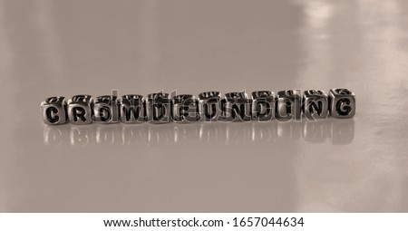 Crowdfunding -  word from metal blocks - concept sepia tone photo on shine background
