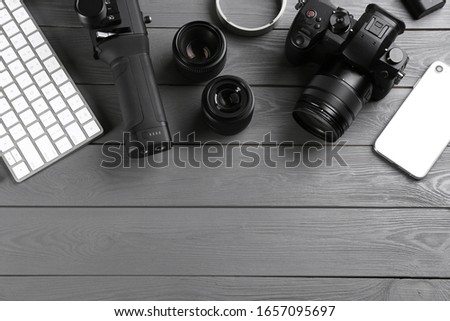 Flat lay composition with camera and video production equipment on grey wooden table. Space for text