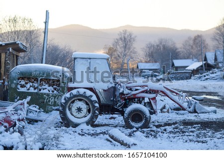 A blue tractor stands by a village house in snowfall in the village of Dersu in the Primorsky Territory in Russia. The village of Dersu is inhabited by Hispanic Old Believers.