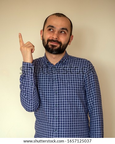 Portrait of young Turkish man has an idea, pointing with finger up looking up. Thoughtful guy solved a problem problem. Face expression,body language, life perception creativity.