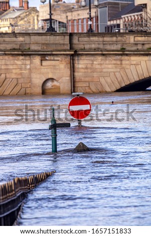 A No Entry sign standing in flood water which has blocked the road