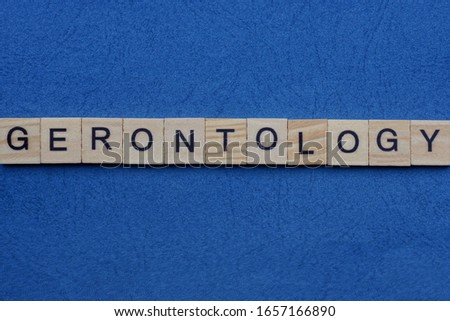 gray word gerontology from small wooden letters on a blue table