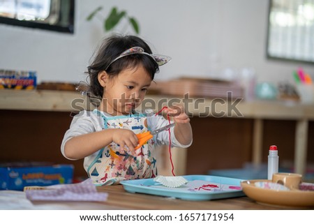 Active Asian girl concentrated playing at kindergarten.