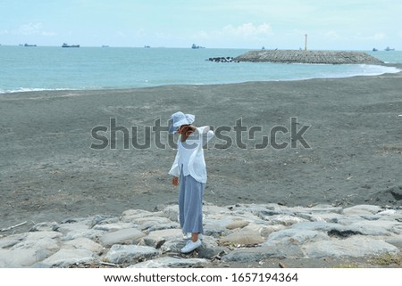 Happy women stroll by the sea in a white shirt with a hat.Quote background.Minimal.