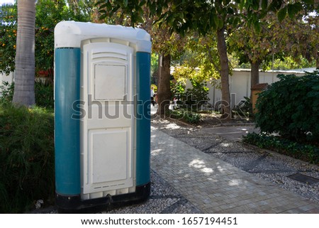 A public toilet surrounded by greenery in a public park under the sunlight