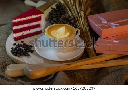 art latte hot coffee white cup with Red velvet cake and  coffee bean on wooden ,food and drink concept 