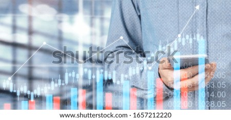 Hand holding smartphone device and touching screen. Stock exchange market concept. businessman trader looking on with graphs analysis candle