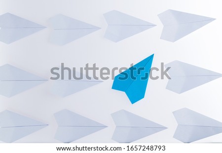 Blue origami plane stand out from the crowd.