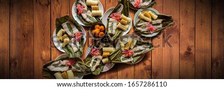 Top view of dishes with fish Maitos, typical food of the Ecuadorian Amazon, accompanied with cassava, cooked banana and salad on a wooden table Royalty-Free Stock Photo #1657286110