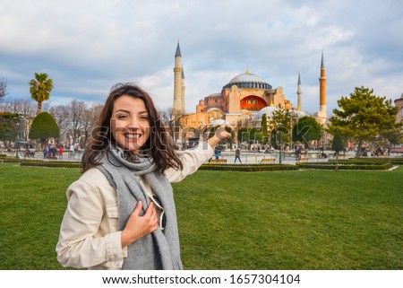 Beautiful woman traveler tourist shows an ancient Mosque at Sultanahmet Park,a popular destination for Tourists and locals in Istanbul,Turkey